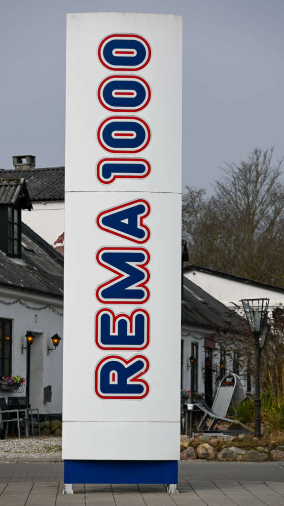 Rema 1000 skllt med Blovstrød Kro i Baggrunden